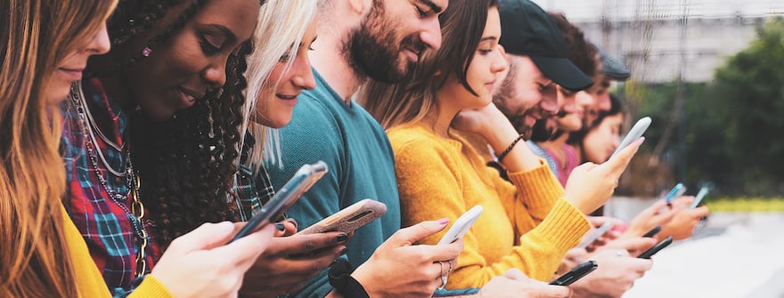 A group of Gen Zers on their phones that represent prospective clients and target market for a mental health practice and the importance of creating a marketing strategy that accounts for their digital habits